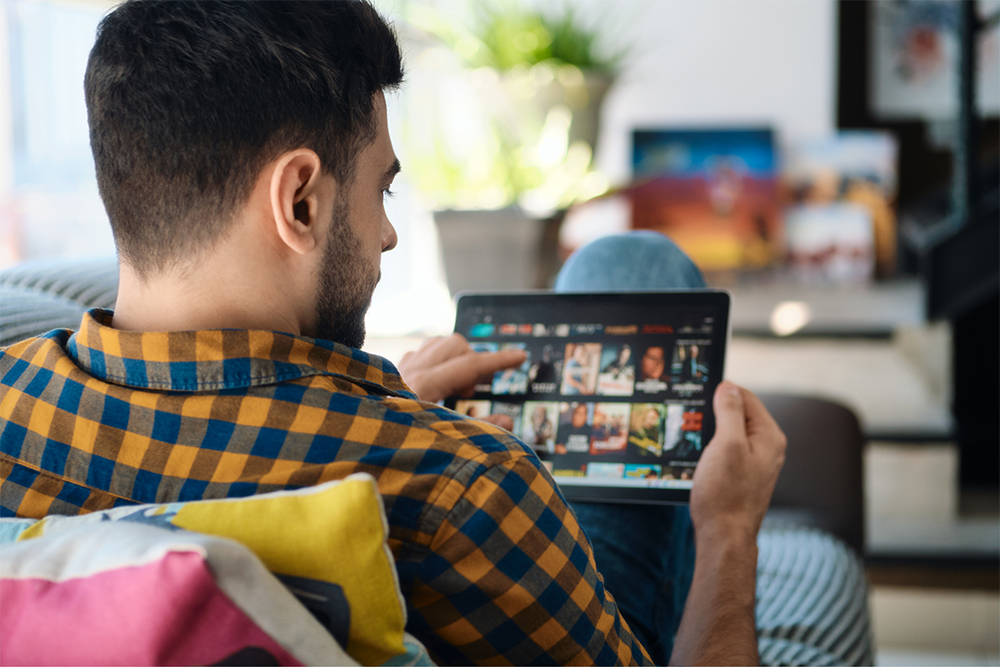 A viewer browsing a streaming catalogue on a laptop at home