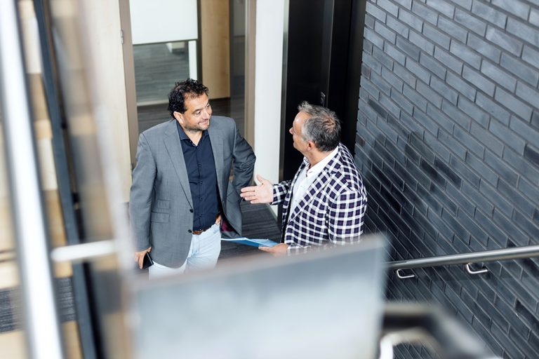 Two people shaking hands in an office doorway